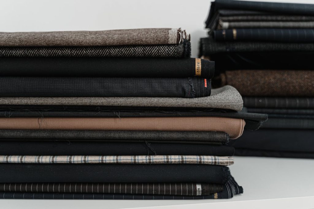 A neatly arranged pile of diverse fabrics, ideal for a fashion designer or tailor's workshop.